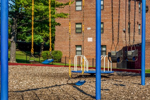 a playground with swings and a building in the background