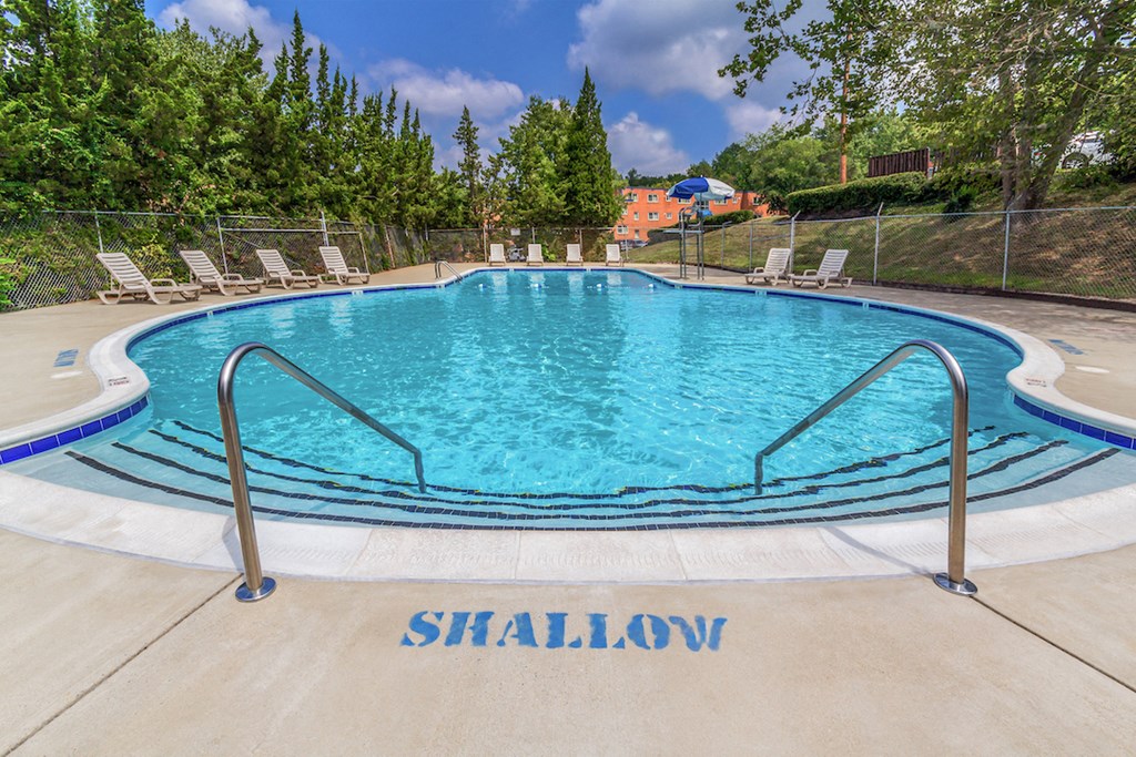 a swimming pool with chairs and a fence around it