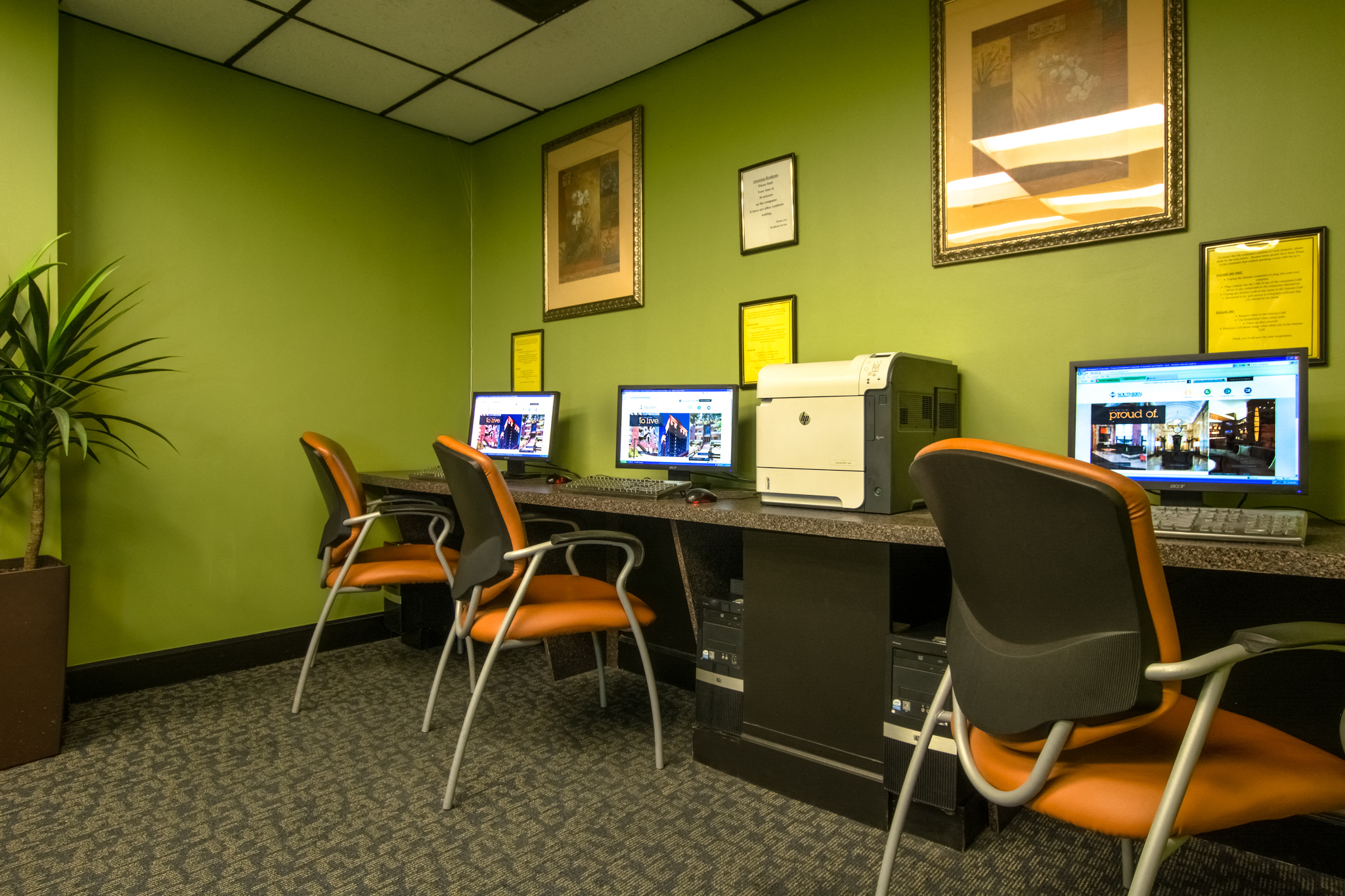 a desk with four computers and chairs in a room