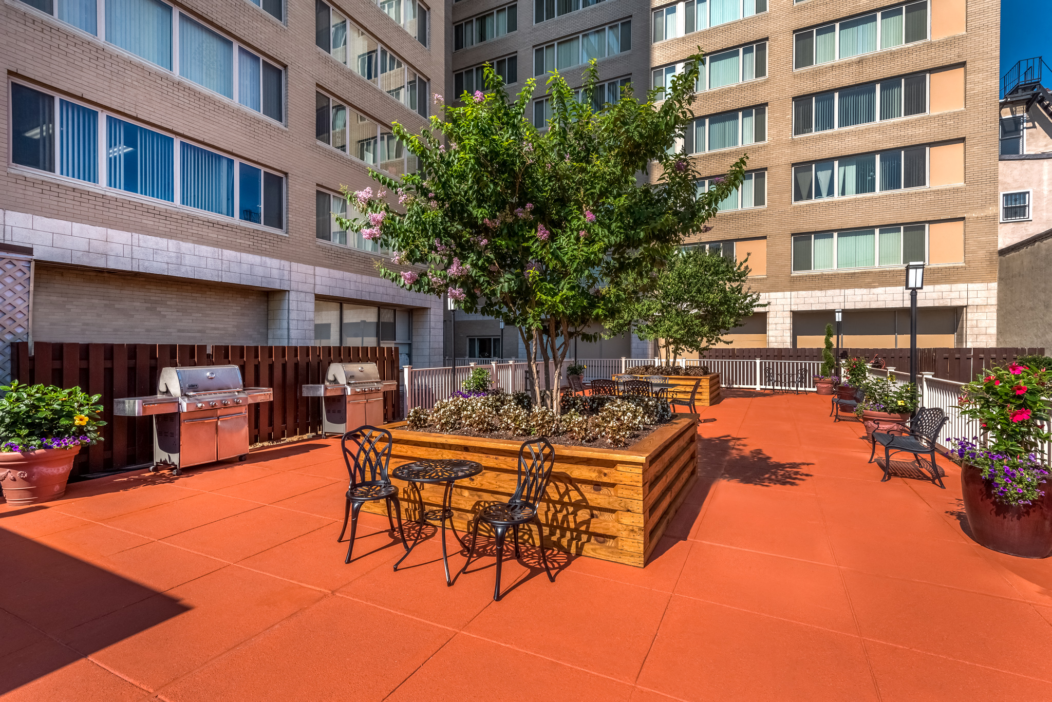 an outdoor patio with chairs and a tree in front of an apartment building