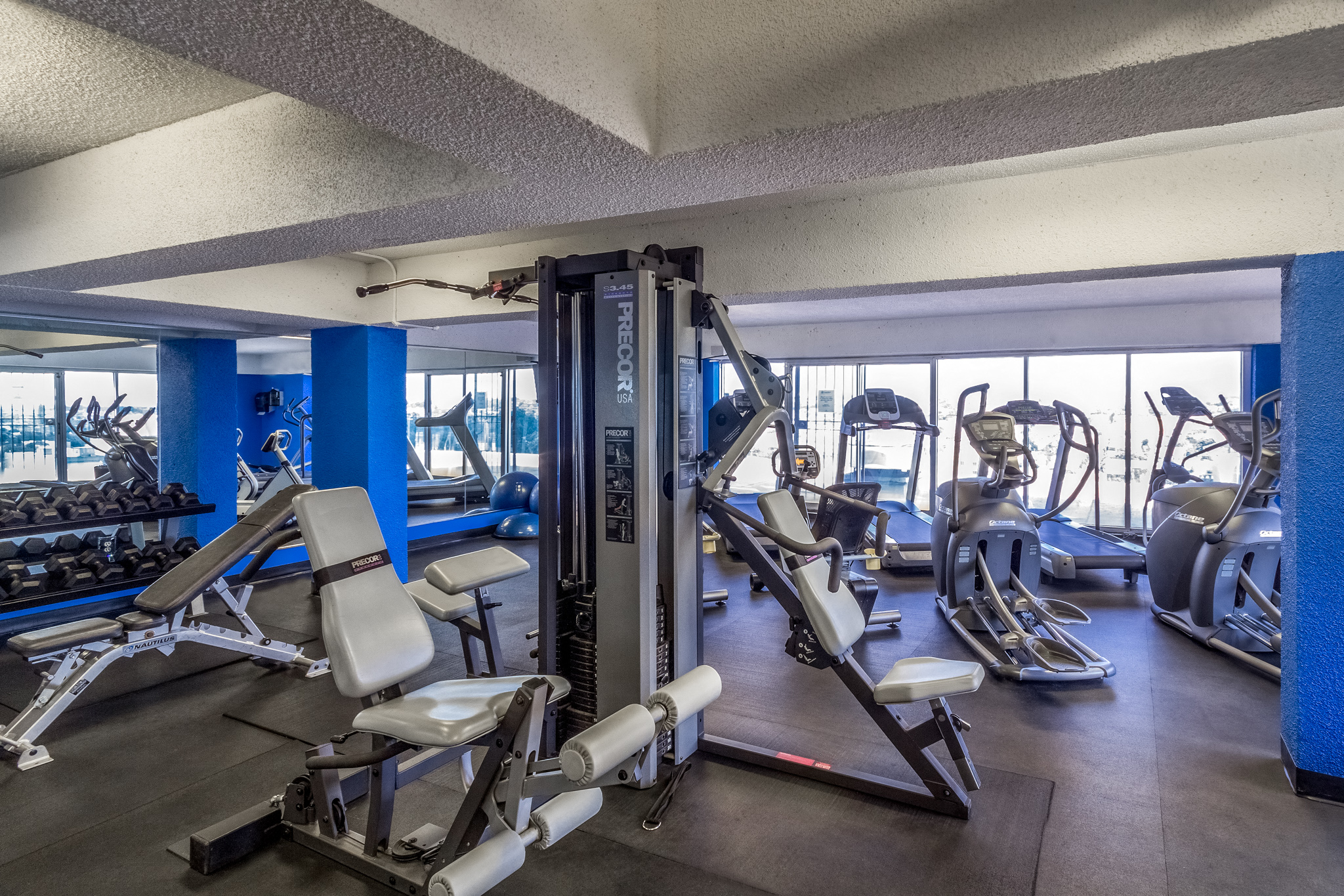 a gym with treadmills and other exercise equipment in a building with windows
