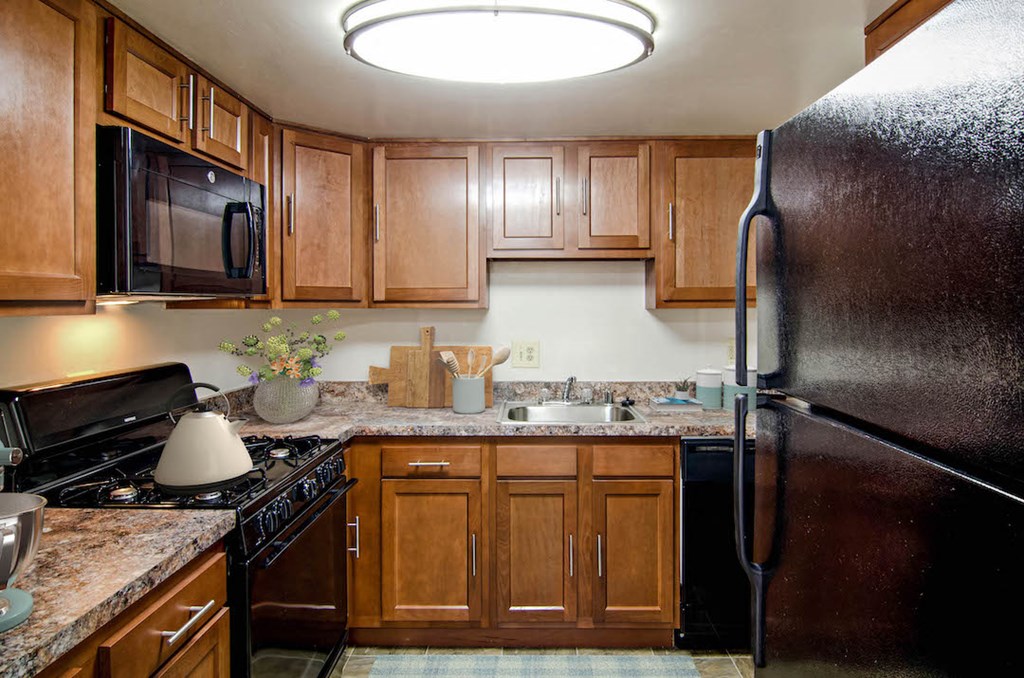 a kitchen with wooden cabinets and a black refrigerator