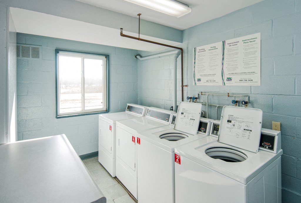 a laundry room with four washer and dryers and a window
