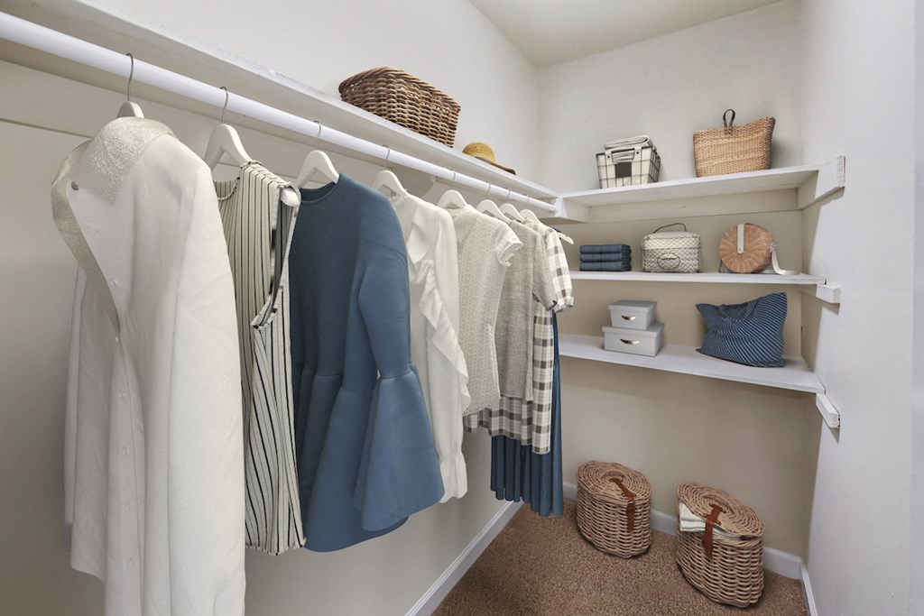 a walk in closet with white shelves and a rack of clothes
