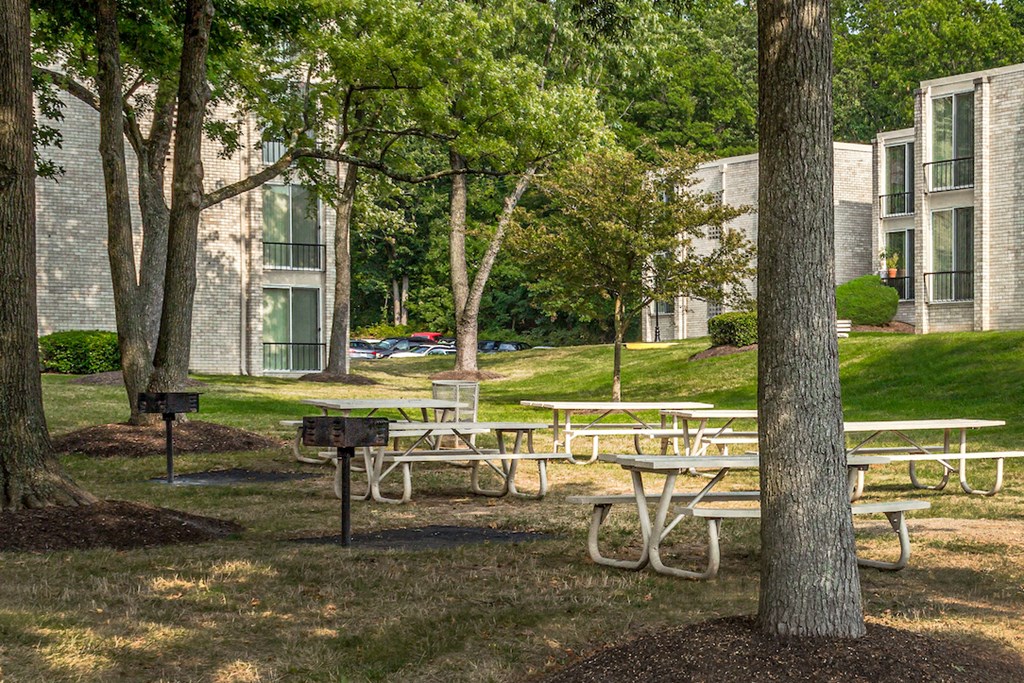 a group of picnic tables in a park in front of an apartment building