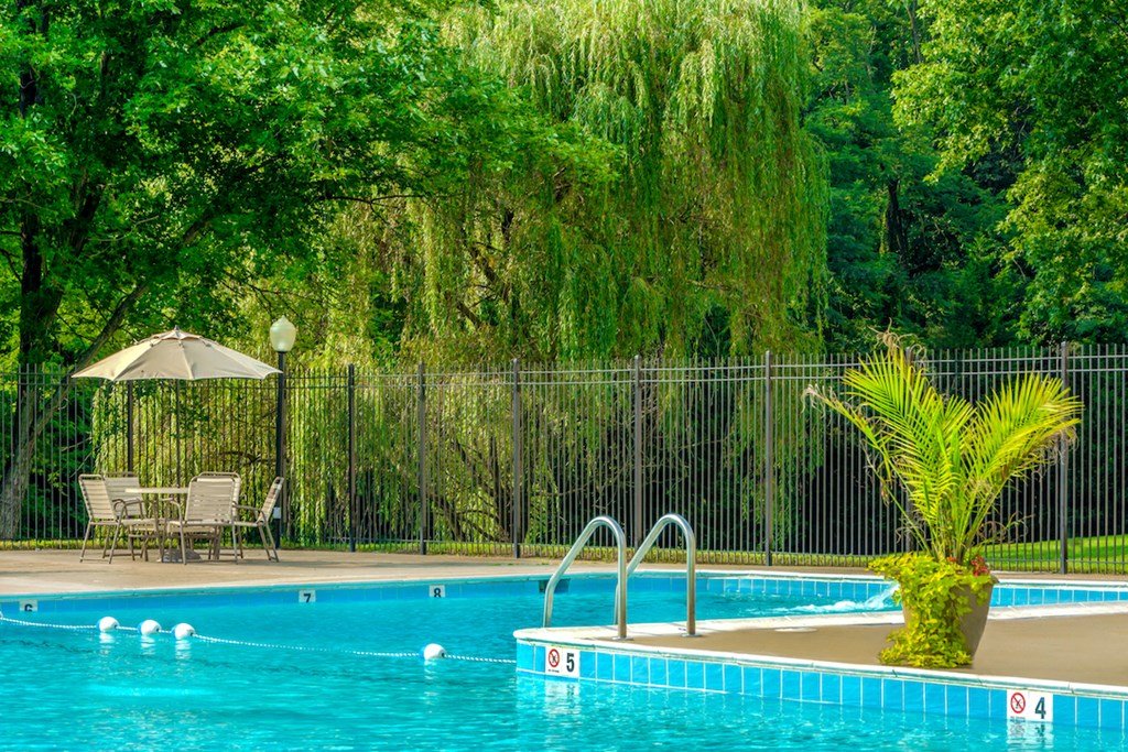 a swimming pool with chairs and an umbrella next to it