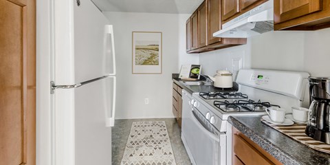 full kitchen with white appliances and wood cabinets at the preserve at polk apartments