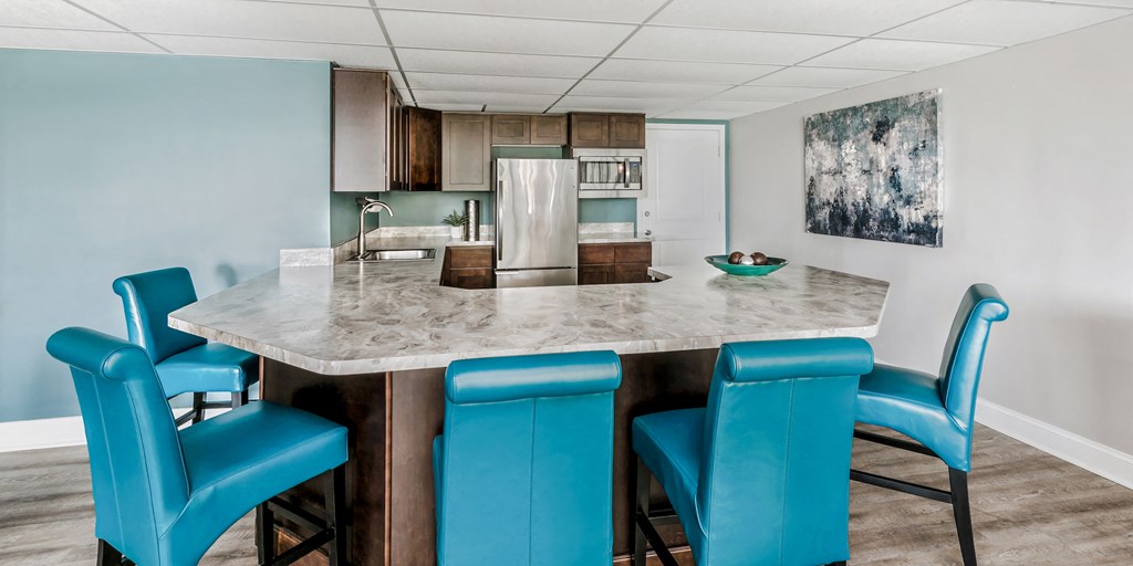 a kitchen with a marble counter top and blue chairs