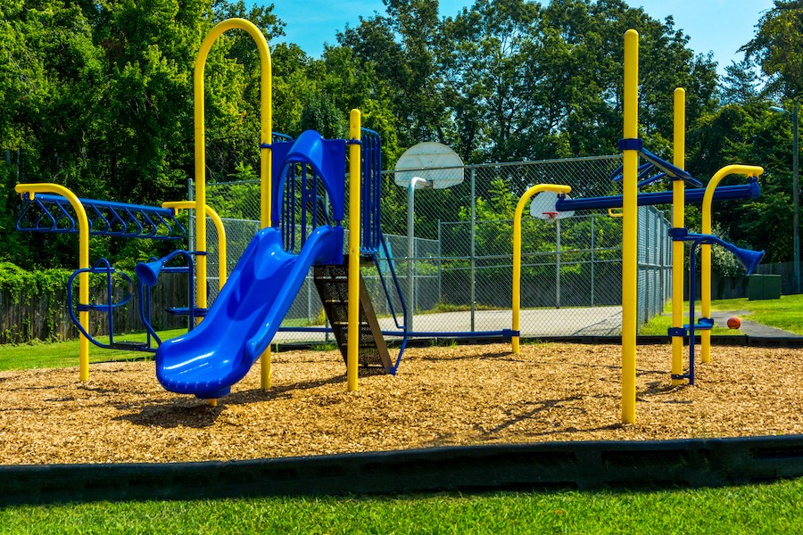 a playground with a blue slide and a basketball court