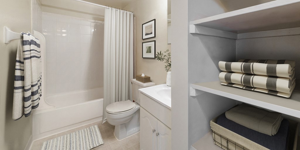 a bathroom with a toilet and a shower and a shelf with striped towels