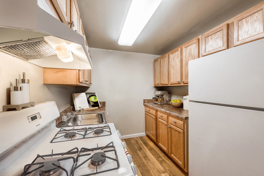 a kitchen with white appliances and wooden cabinets and a white refrigerator