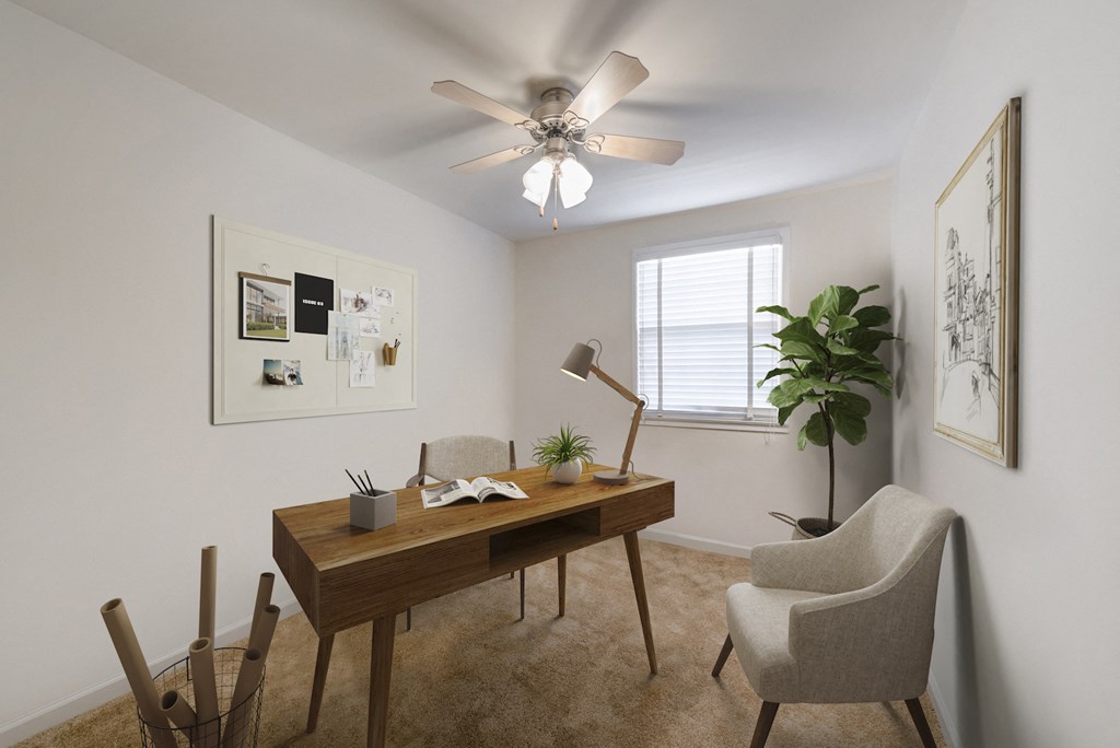 furnished bedroom with ceiling fan and desk at the district flats apartments