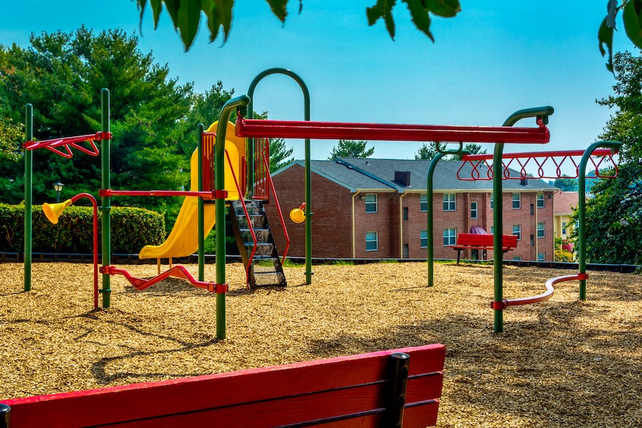 a playground with a yellow swing set and a red bench