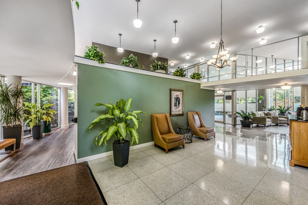 a lobby with plants and chairs and a green wall