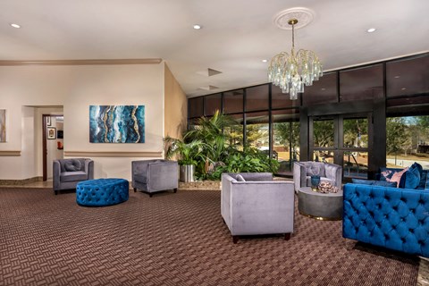the lobby of a hotel with blue chairs and a chandelier