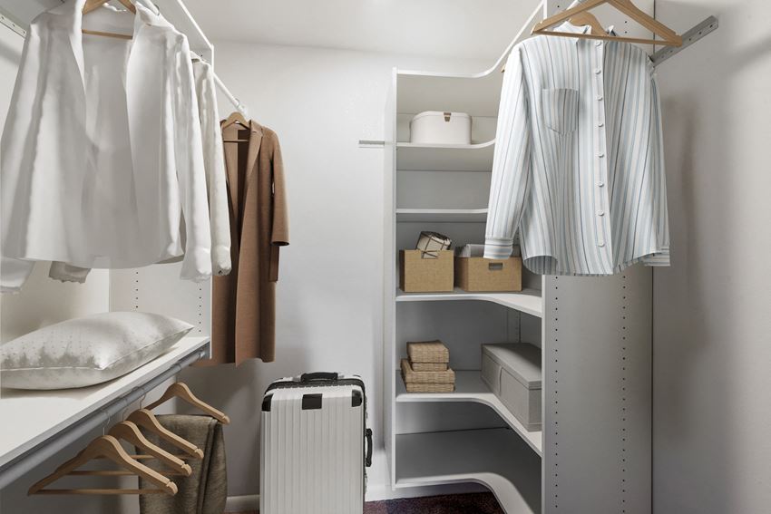 a walk in closet with a clothes rack and a suitcase