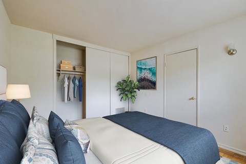 A bedroom with a bed, couch, and a painting on the wall.