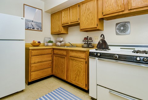a kitchen with a white stove and refrigerator and wooden cabinets