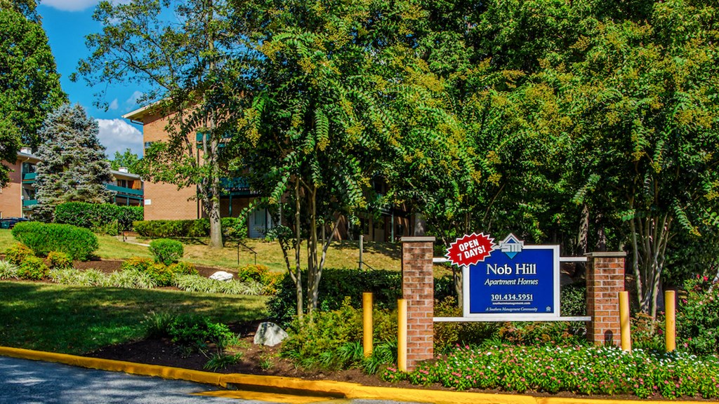 our sign in front of our building with trees and bushes