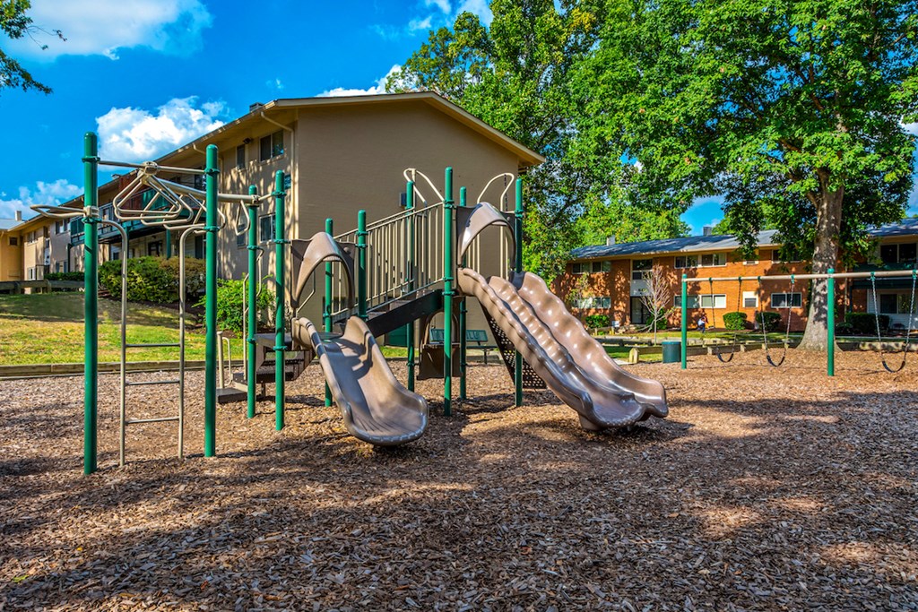 a playground with two sets of slides in front of a building