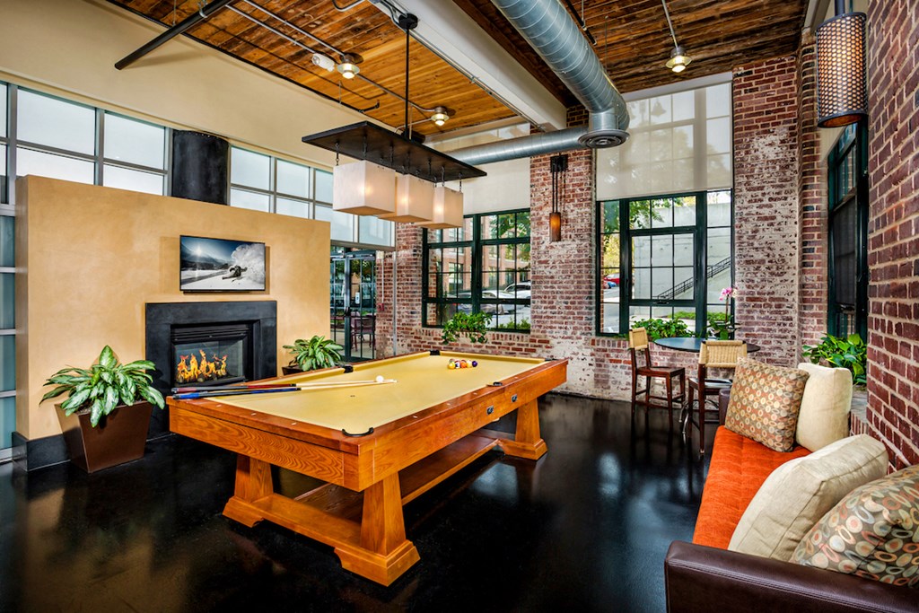 a pool table in a living room with a brick fireplace