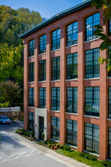a red brick building with large windows and a street in front