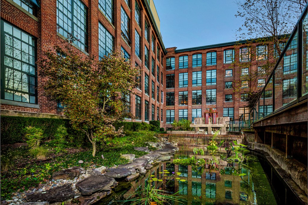 a courtyard with a pond in front of a brick building