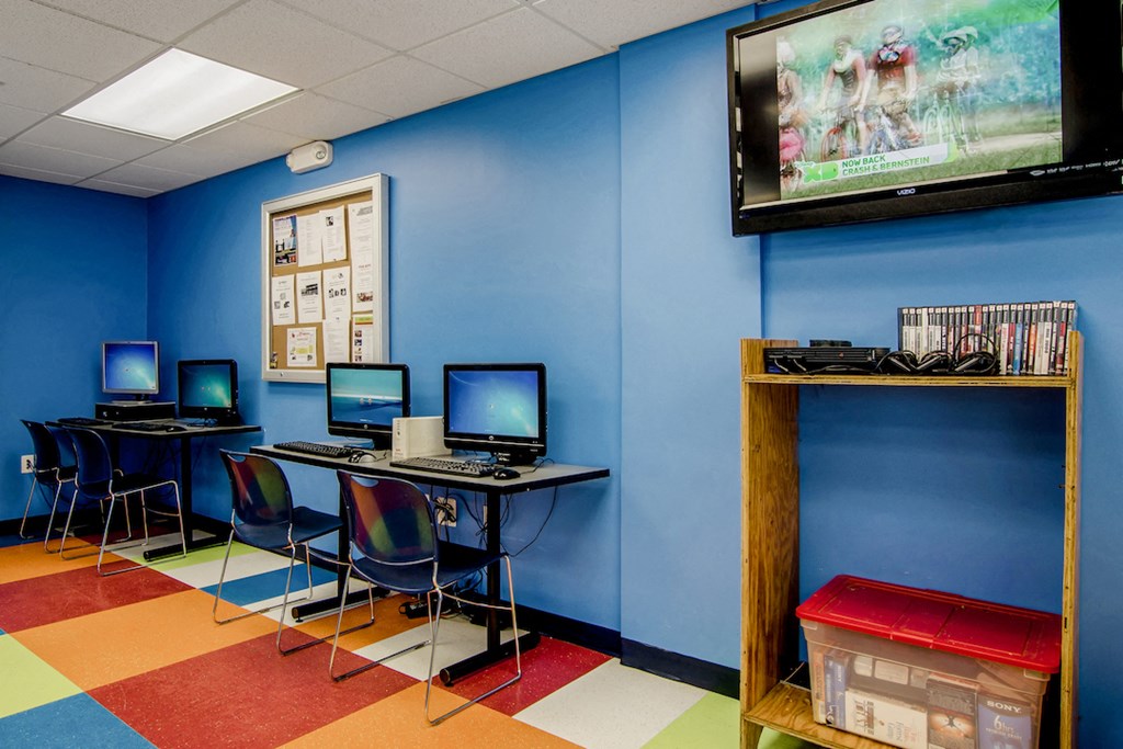 a computer room with three computers on a desk and a television