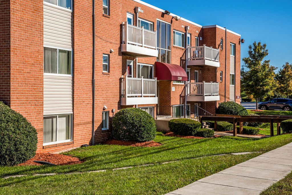 an exterior view of a brick apartment building with a sidewalk