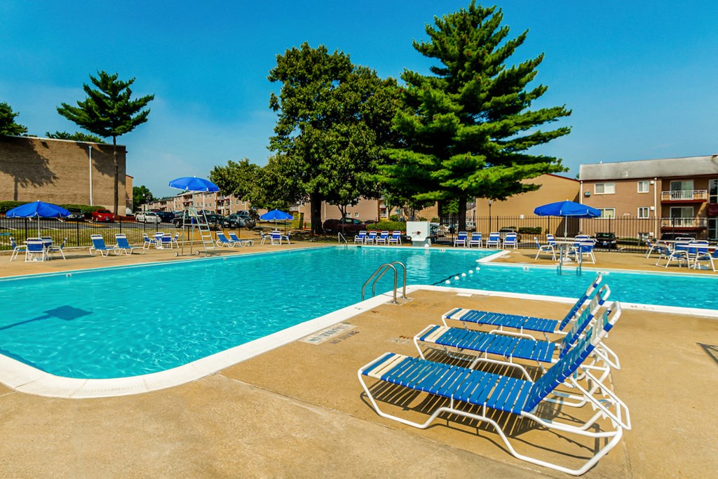 a swimming pool with blue chairs and umbrellas next to a building