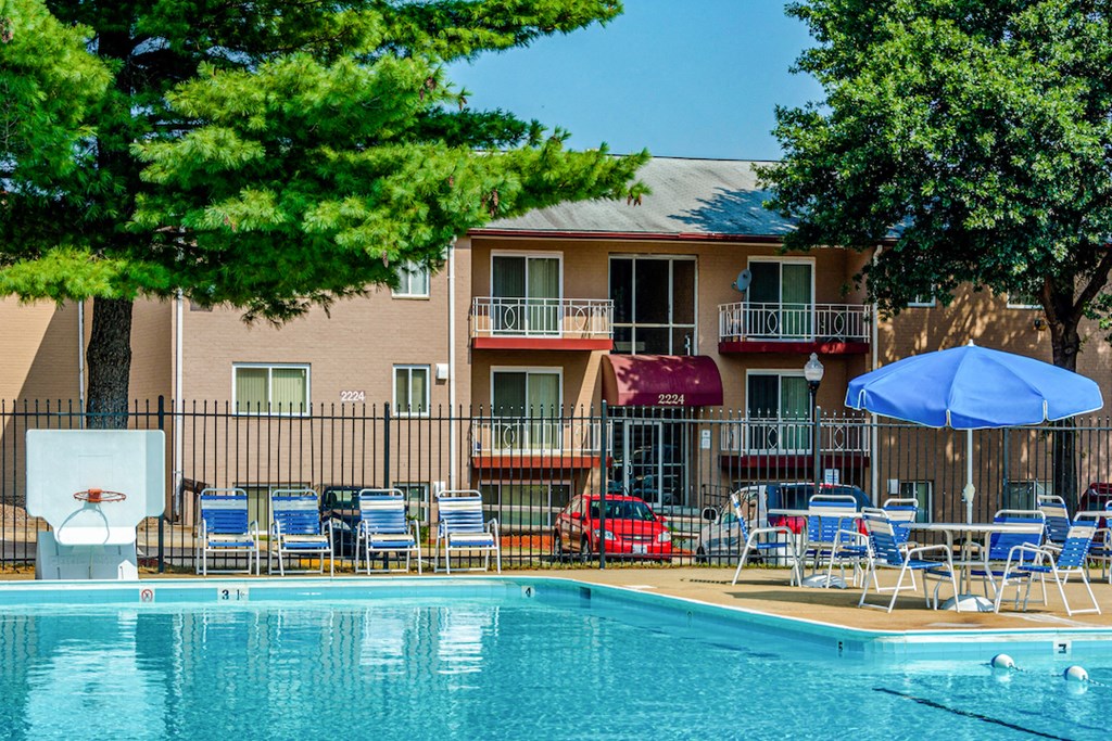 a swimming pool with chairs and a building in the background