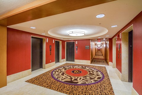 a long hallway with red doors and a carpet on the floor