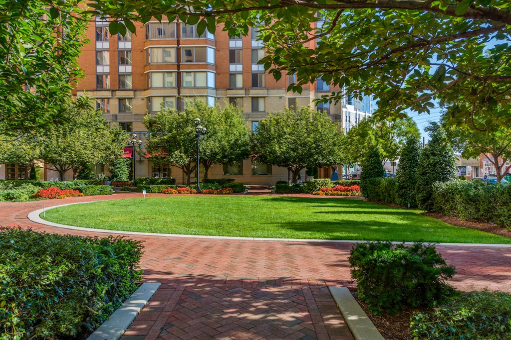 a courtyard with grass and trees in front of an apartment building