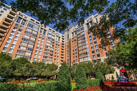 an exterior view of a large apartment building with trees and gardens