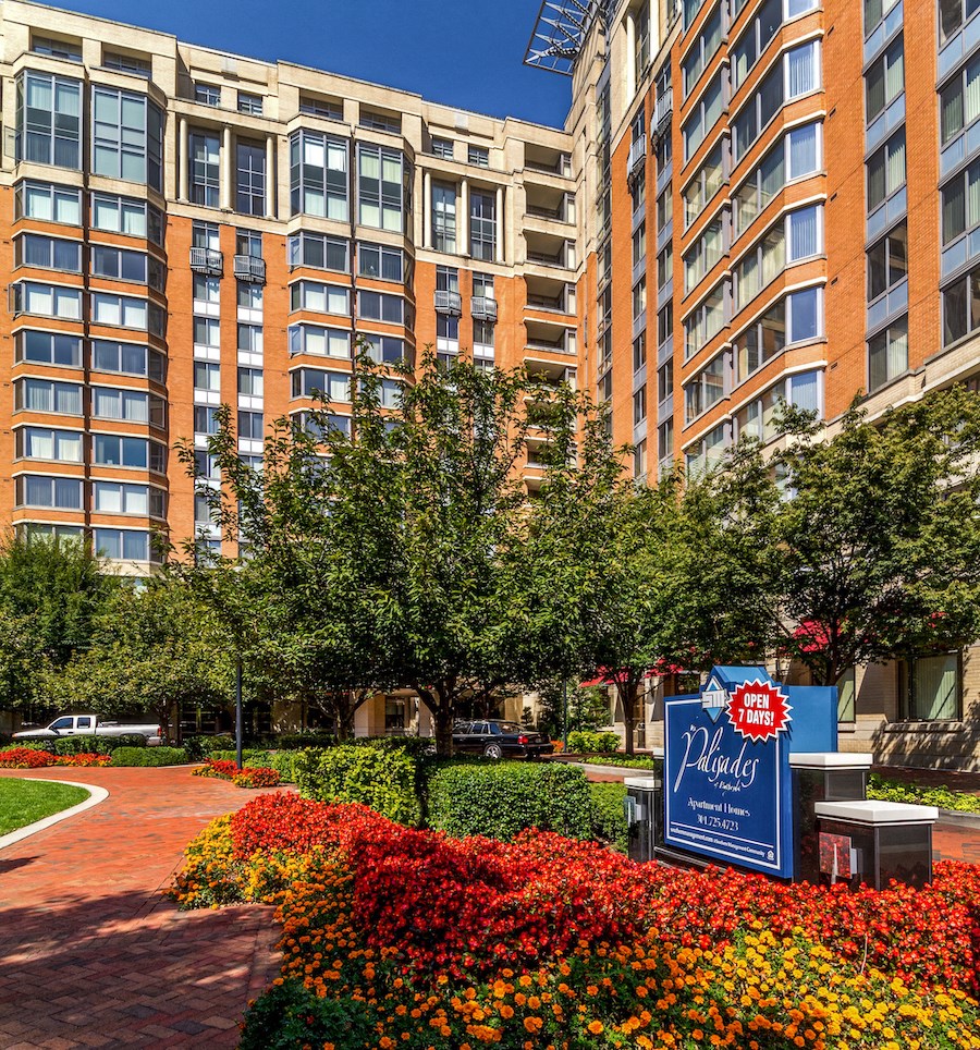 a park with flowers and a sign in front of a building