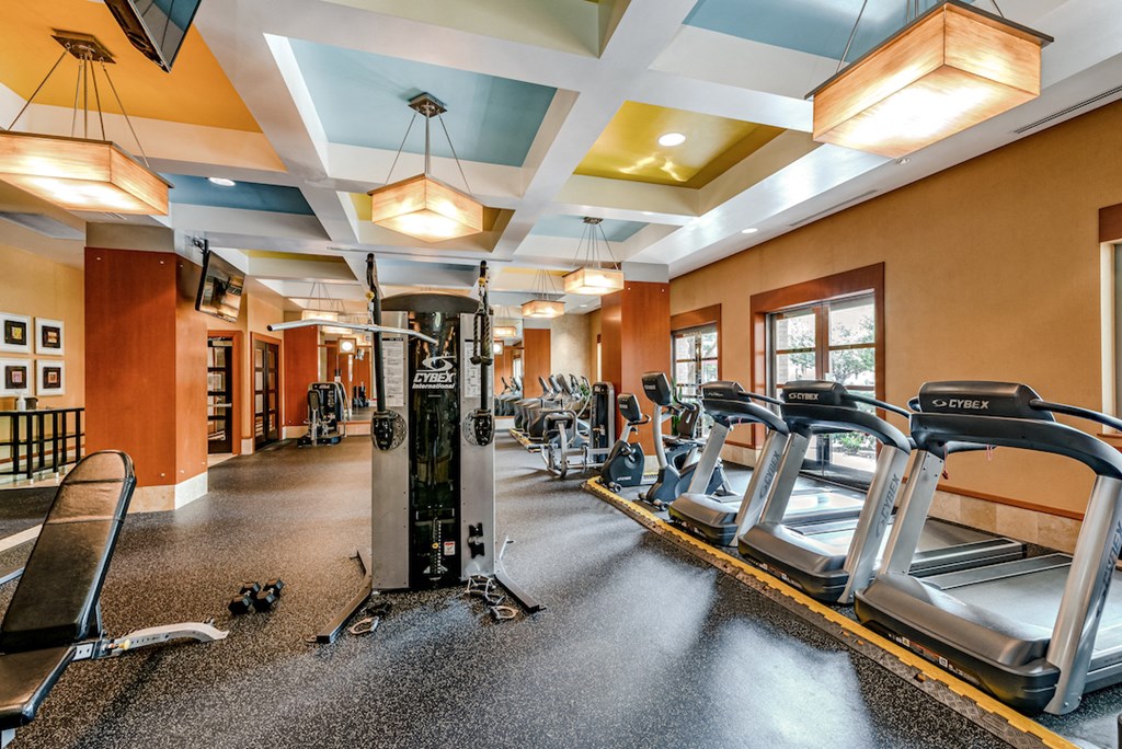 a gym with cardio equipment on the floor and windows