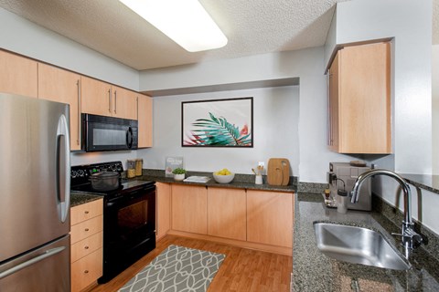 full kitchen with granite countertops and stainless steel appliances at the flats at west end