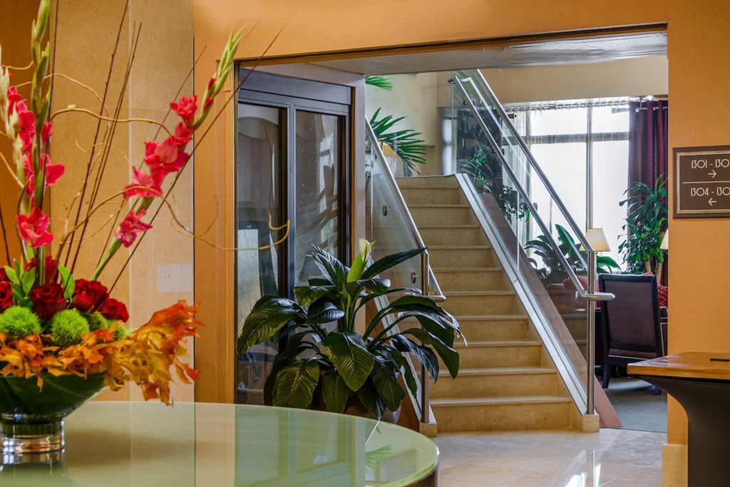 a view of the lobby of a hotel with stairs and a vase of flowers