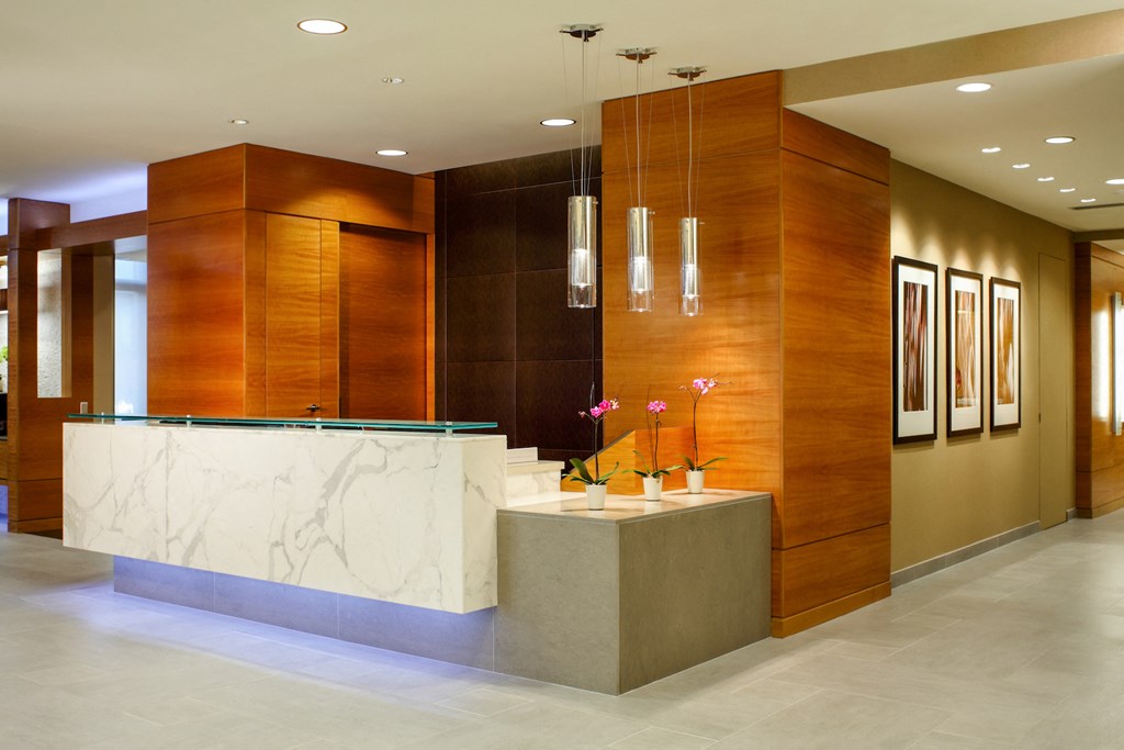 the lobby of a hotel with a marble reception desk and wooden walls