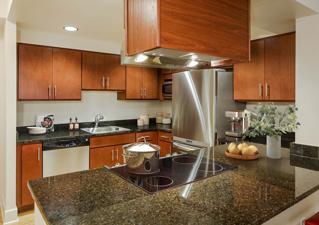 a kitchen with granite counter tops and a stainless steel refrigerator