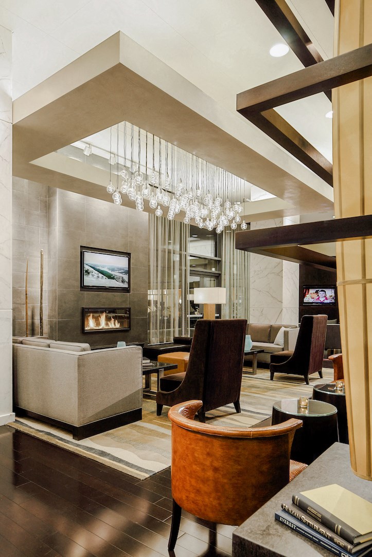 a living room with couches chairs and a fireplace and a chandelier