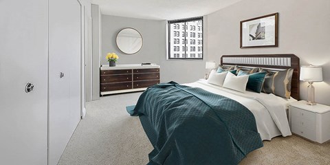 A bedroom with a bed, nightstand, and a dresser with a mirror.