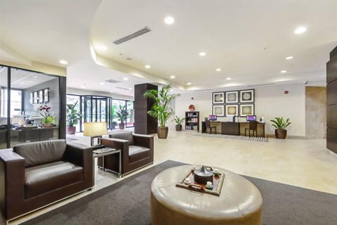 A modern living room with a brown leather couch and a round ottoman.
