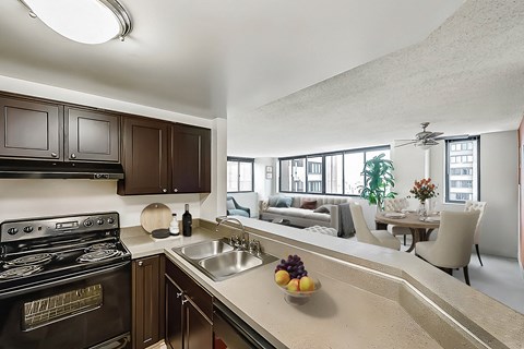 A kitchen with a black stove top oven and a counter top with a bowl of fruit on it.