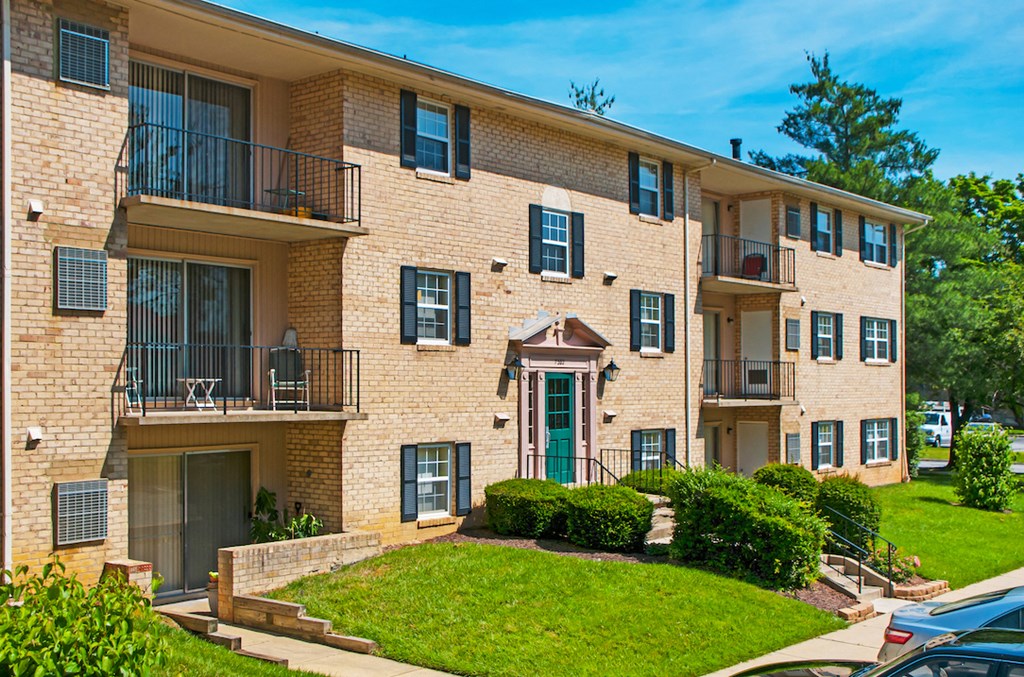 a brick apartment building with balconies and a green lawn
