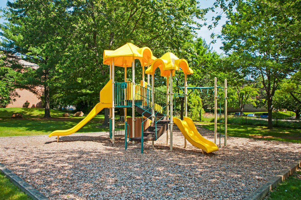 a playground with a yellow playset in a park