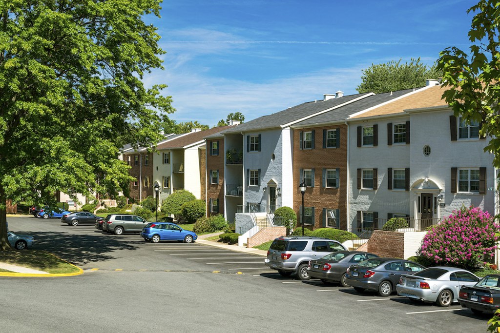 a parking lot with cars in front of an apartment building