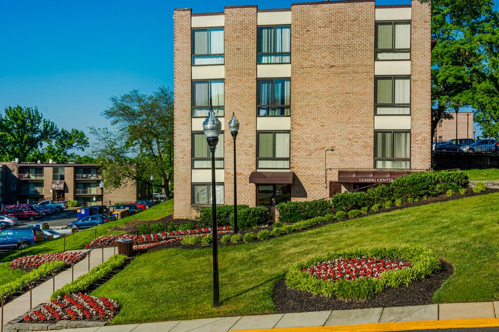 an apartment building with a lawn and flower garden in front of it