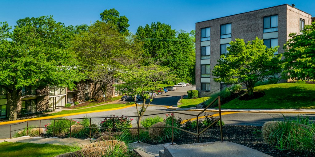 an apartment building on the corner of a street with trees