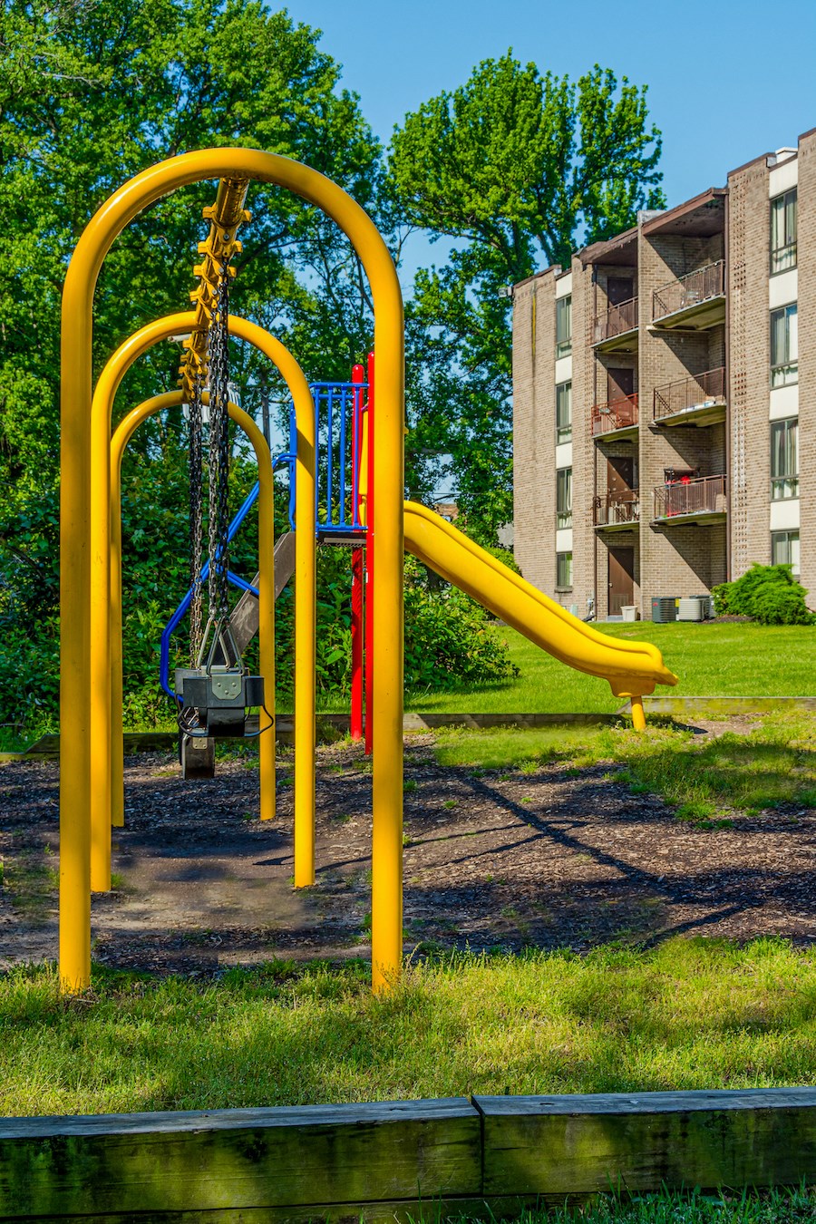 a playground with a swing set in front of an apartment building